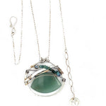 A sterling silver necklace with a moss-colored jade fan gemstone pendant featuring hammered bronze, oxidized sterling silver twist wire, and micro faceted ombre blue tourmaline gemstones, crystal, and pyrite.