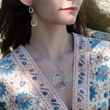 A sterling silver nautilus shell necklace with micro-faceted aquamarine and crystal beads along bronze lines, culminating in a faceted rose quartz gemstone center.