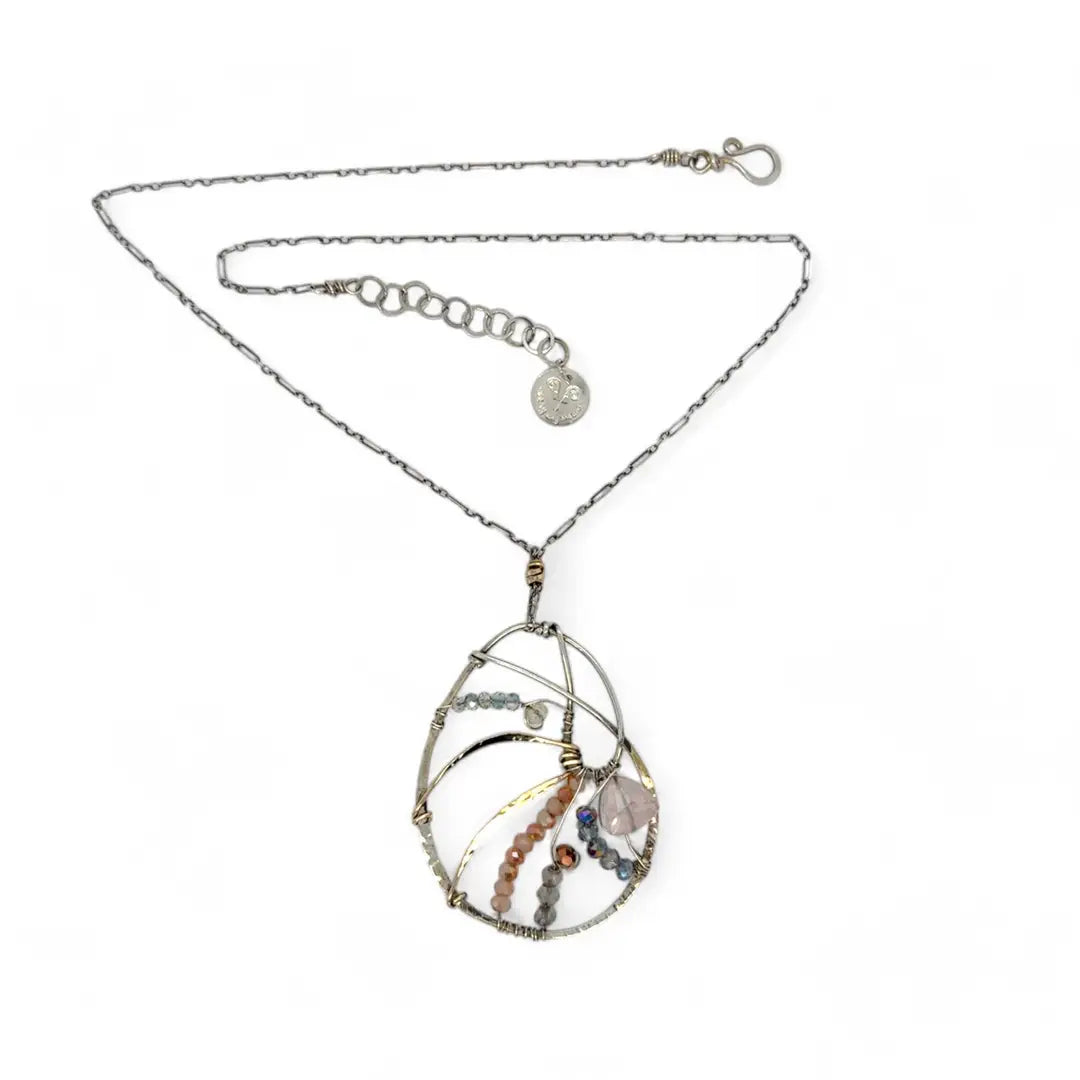 A sterling silver nautilus shell necklace with micro-faceted aquamarine and crystal beads along bronze lines, culminating in a faceted rose quartz gemstone center.