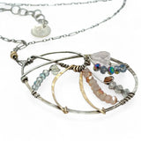 A sterling silver nautilus shell necklace with micro-faceted aquamarine and crystal beads along bronze lines, culminating in a faceted rose quartz gemstone center.