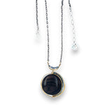 A necklace with a smooth brown jasper round gemstone, surrounded by faceted pyrite, set in hand-formed brass, with an adjustable darkened chain and sterling silver clasp.