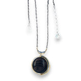 A necklace with a smooth brown jasper round gemstone, surrounded by faceted pyrite, set in hand-formed brass, with an adjustable darkened chain and sterling silver clasp.