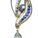 Sterling silver and brass wing shapes combined to make one pendant featuring moonstone, blue crystal, labradorite, kyanite, and lapis gemstones with a blue quartz hanging drop to complete the necklace