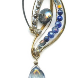 Sterling silver and brass wing shapes combined to make one pendant featuring moonstone, blue crystal, labradorite, kyanite, and lapis gemstones with a blue quartz hanging drop to complete the necklace