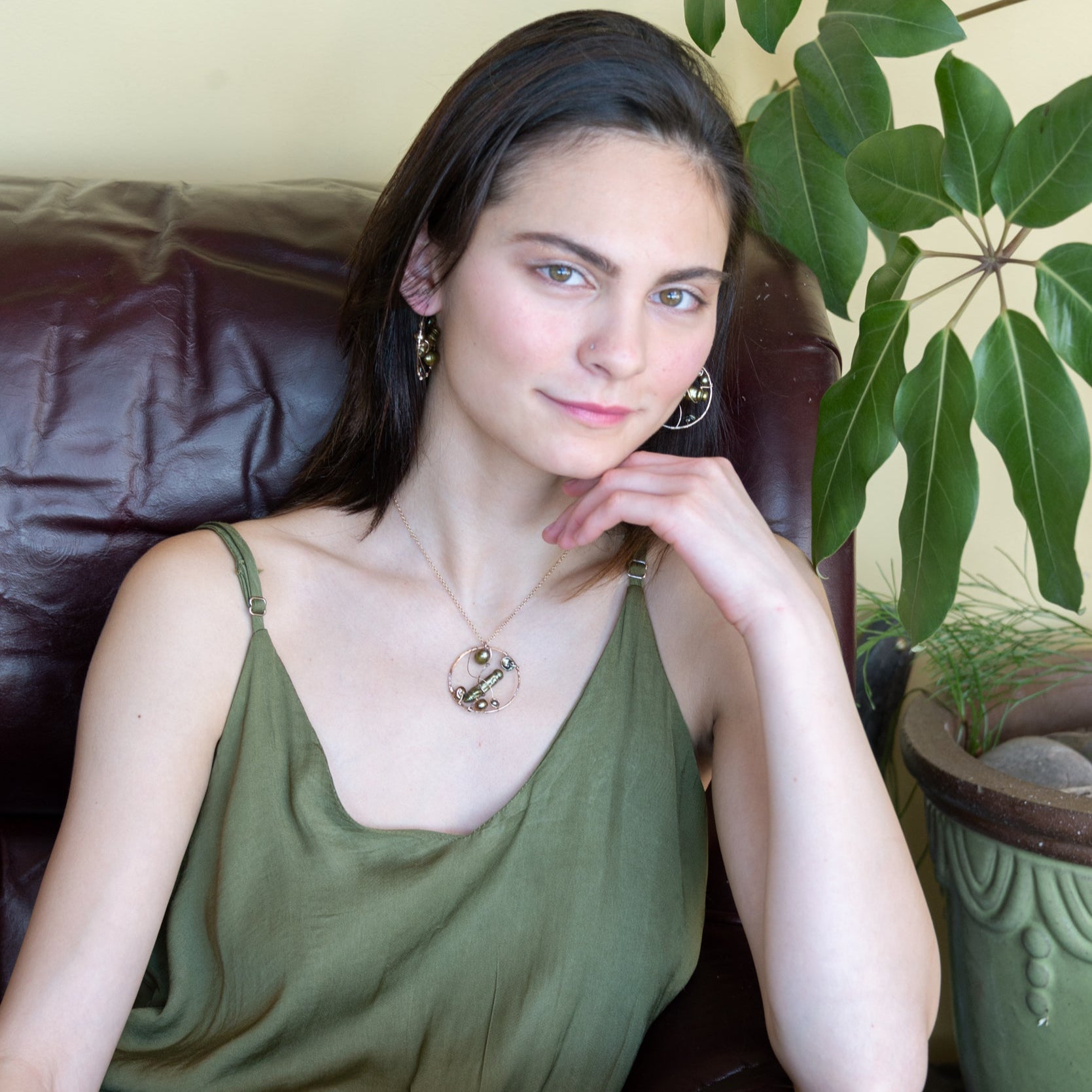 A collection of olive green fresh water pearls are woven in layers of gold filled hammered wire onto a handmade circle gold pendant necklace