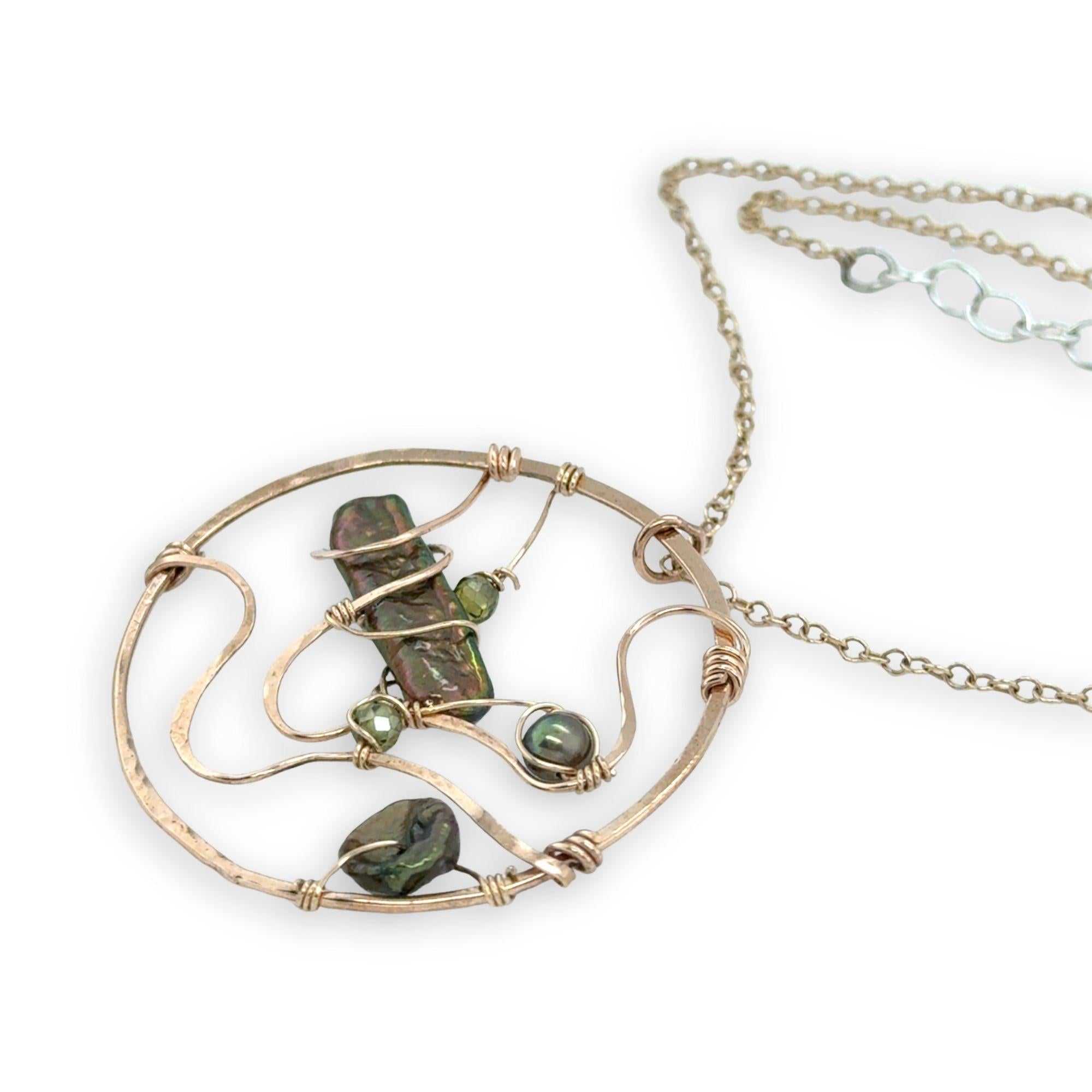 A collection of olive green fresh water pearls are woven in layers of gold filled hammered wire onto a handmade circle gold pendant necklace