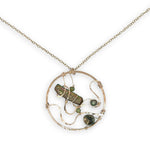 A collection of olive green fresh water pearls are woven in layers of gold filled hammered wire onto a handmade circle gold pendant necklace