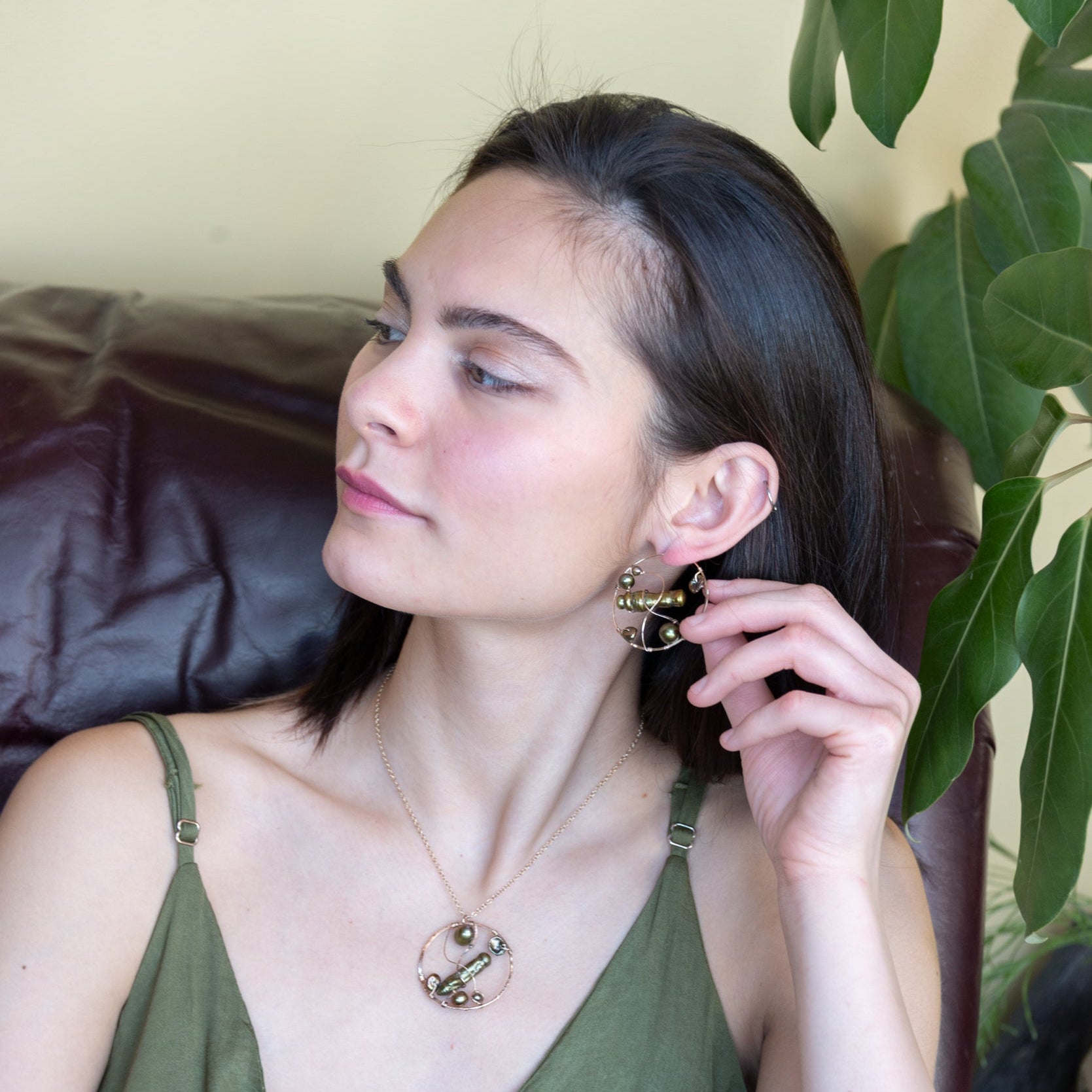 Gold filled hoop earrings embroidered with a variety of different shaped olive green fresh water pearls