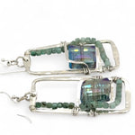 A pair of sterling silver hammered rectangle earrings with square cut blue-green crystals and faceted emerald gemstone cubes.