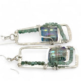 A pair of sterling silver hammered rectangle earrings with square cut blue-green crystals and faceted emerald gemstone cubes.