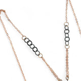 A darkened sterling silver pallete pendant necklace with bronze hammered swirls, featuring a series of faceted gemstones including amethyst and rhodocrosite, peach fresh water coin pearl, and crystal, complemented by a rose gold chain and a silver textured chain.