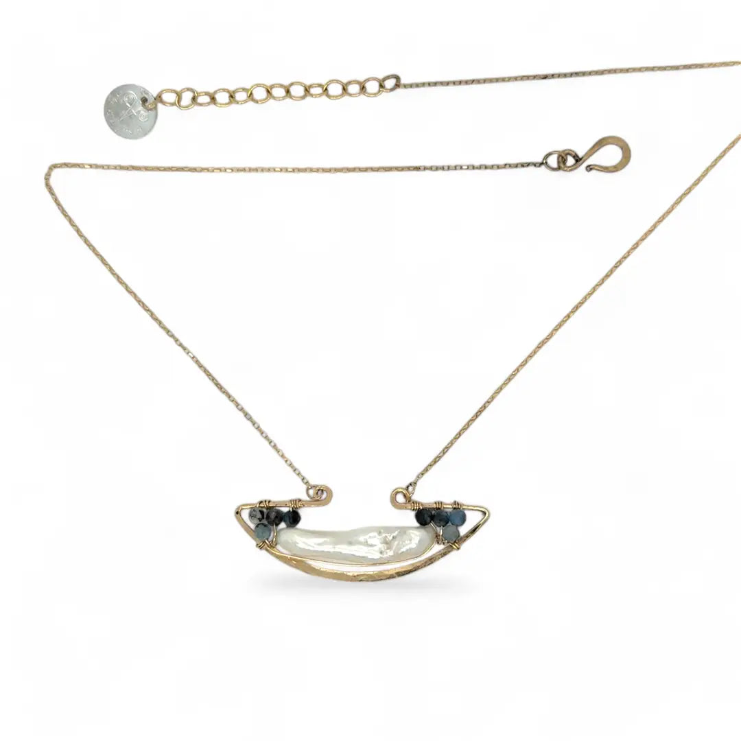 A gold-filled chain necklace with a boat-shaped brass pendant featuring a freshwater pearl stick and aquamarine gemstones at the bow and stern.