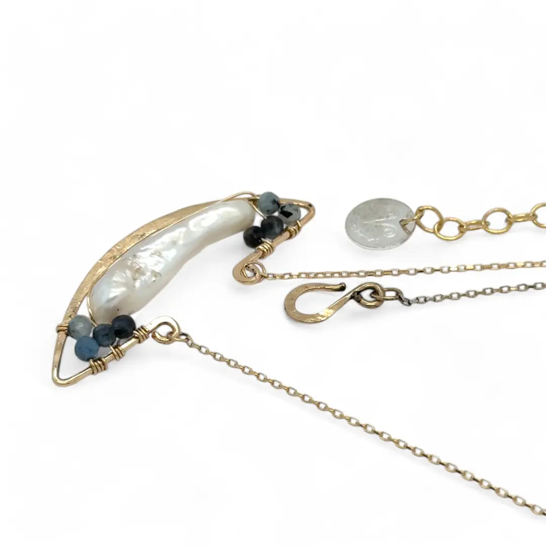 A gold-filled chain necklace with a boat-shaped brass pendant featuring a freshwater pearl stick and aquamarine gemstones at the bow and stern.