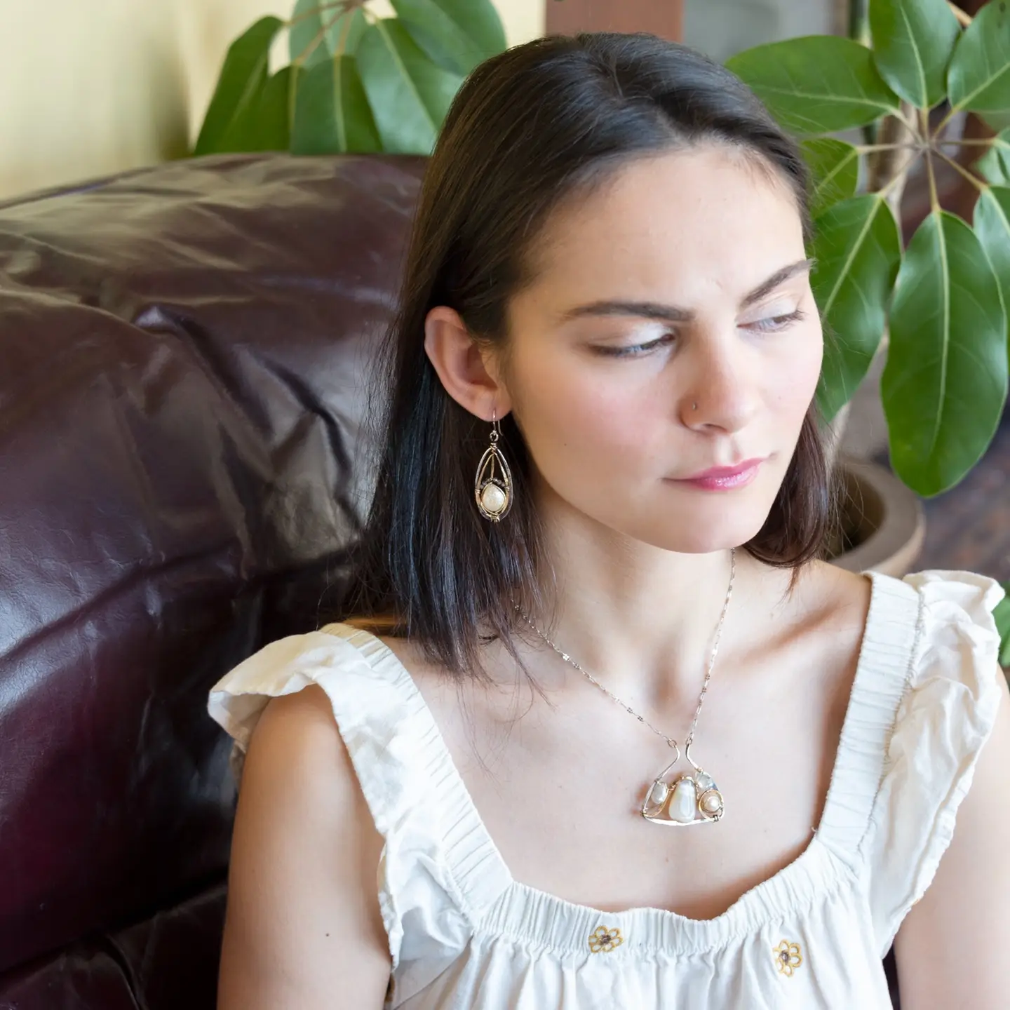 A pair of pearl drop earrings with hammered brass and oxidized sterling silver, featuring micro faceted rutilated quartz details.