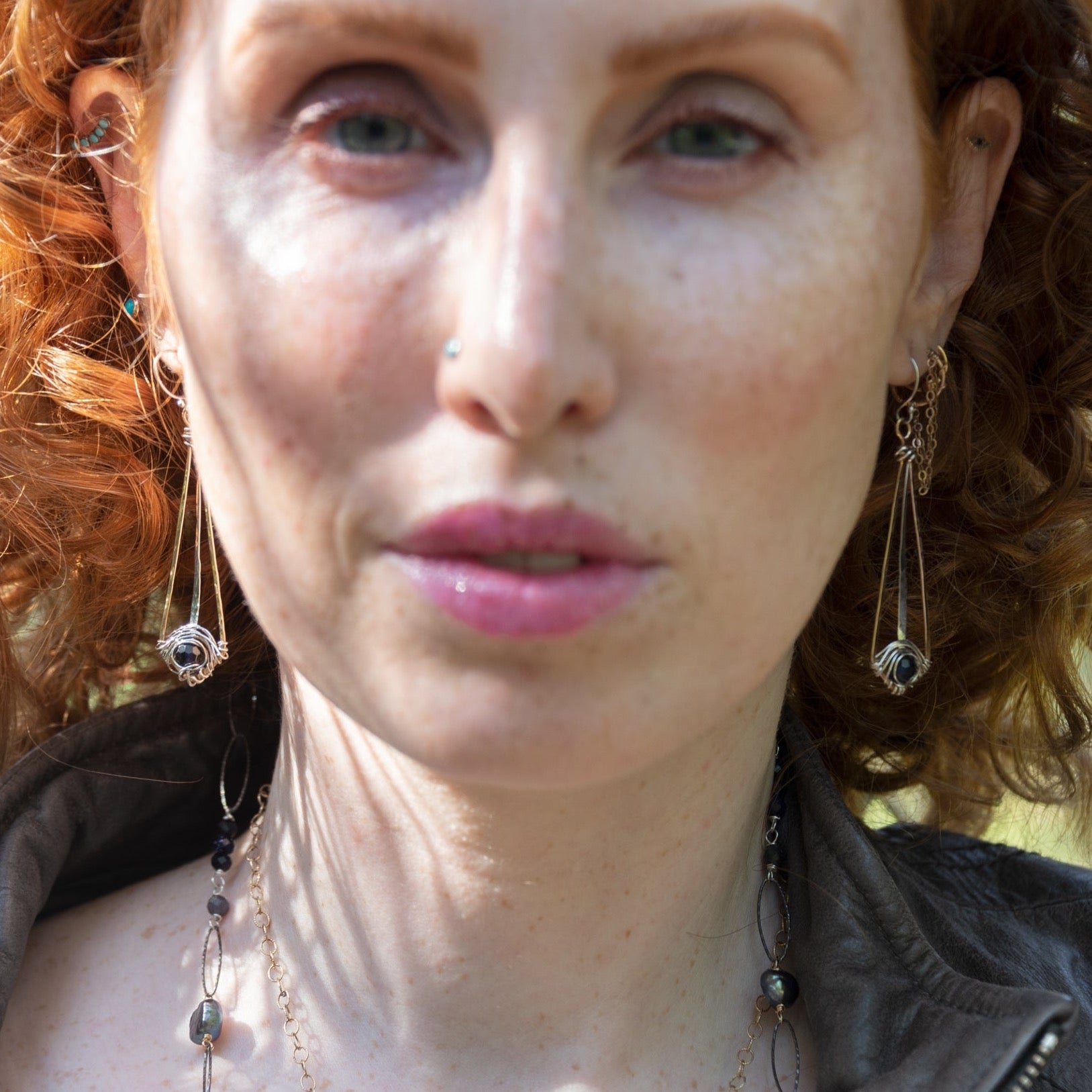 Long and lean brass earrings with sterling silver weaving around a dark iolite faceted gemstone