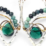 A pair of sterling silver leaf earrings with faceted green amethyst and blue tourmaline gemstones, wrapped in hand-formed hammered brass with sterling silver tube chain tops