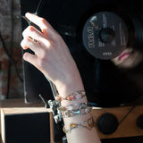 An oxidized sterling silver cuff bracelet with gold-filled wraps, featuring pink opal gemstones and rhodochrosite on a hammered bronze structure