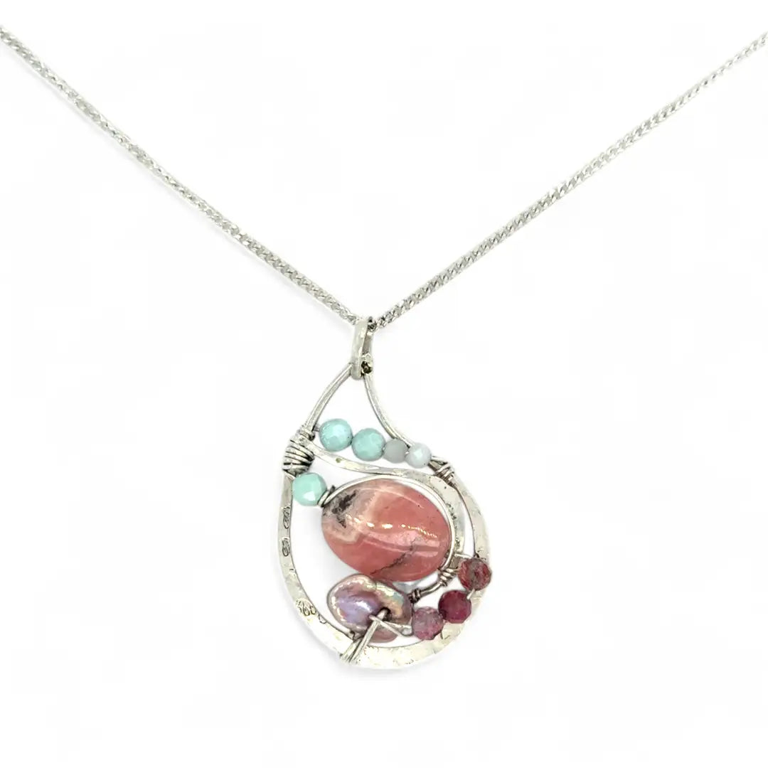 smooth rhodochrosite, pink fresh water pearl, pink tourmaline, moonstone, and larimar gemstones fill the inside of a floral stamped and hammered sterling silver necklace 