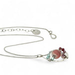 smooth rhodochrosite, pink fresh water pearl, pink tourmaline, moonstone, and larimar gemstones fill the inside of a floral stamped and hammered sterling silver necklace 