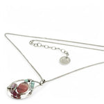 smooth rhodochrosite, pink fresh water pearl, pink tourmaline, moonstone, and larimar gemstones fill the inside of a floral stamped and hammered sterling silver necklace 