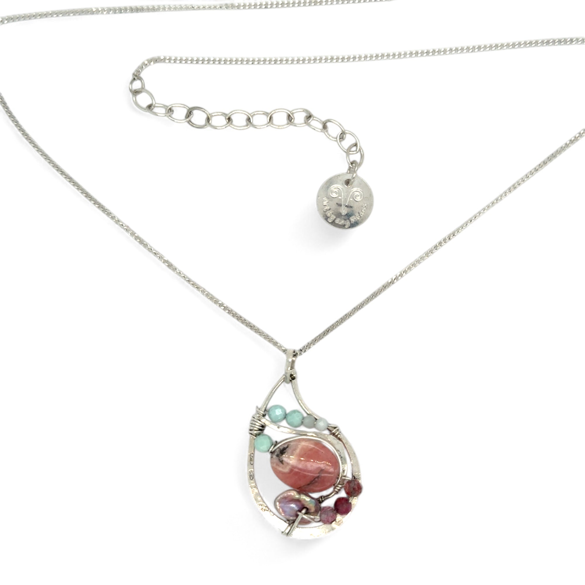 smooth rhodochrosite, pink fresh water pearl, pink tourmaline, moonstone, and larimar gemstones fill the inside of a floral stamped and hammered sterling silver necklace 