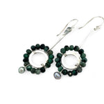Handmade hammered sterling silver rings are outlined with faceted emerald gemstones hanging from a sterling silver hammered and twisted bar, accented with a silver fresh water pearl dangle