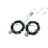 Handmade hammered sterling silver rings are outlined with faceted emerald gemstones hanging from a sterling silver hammered and twisted bar, accented with a silver fresh water pearl dangle