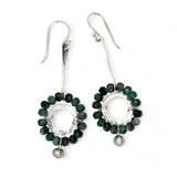Handmade hammered sterling silver rings are outlined with faceted emerald gemstones hanging from a sterling silver hammered and twisted bar, accented with a silver fresh water pearl dangle