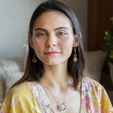 Flashy labradorite faceted coins wrapped in layers of gold filled wire hanging from a hand formed sterling silver twisted bar earring