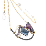 Dark labradorite parallelogram, banded fluorite, purple crystal, and amethyst gemstones ride waves of hammered brass inside a floral stamped and hammered oxidized sterling silver arch pendant on gold filled chain necklace