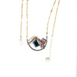 Dark labradorite parallelogram, banded fluorite, purple crystal, and amethyst gemstones ride waves of hammered brass inside a floral stamped and hammered oxidized sterling silver arch pendant on gold filled chain necklace