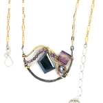 Dark labradorite parallelogram, banded fluorite, purple crystal, and amethyst gemstones ride waves of hammered brass inside a floral stamped and hammered oxidized sterling silver arch pendant on gold filled chain necklace