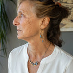 A pair of brass sculptural squiggle earrings with raw kyanite gemstone drops, an assortment of sparkly crystals, and fresh water pearls, featuring gold-filled French hooks.