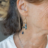 A pair of brass sculptural squiggle earrings with raw kyanite gemstone drops, an assortment of sparkly crystals, and fresh water pearls, featuring gold-filled French hooks.