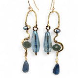 A pair of brass sculptural squiggle earrings with raw kyanite gemstone drops, an assortment of sparkly crystals, and fresh water pearls, featuring gold-filled French hooks.