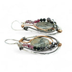 A pair of Prehnite smooth oval earrings with cool inclusions, adorned with hammered bronze, twisted oxidized sterling silver, and micro faceted watermelon tourmaline gemstones, attached to sterling silver French hooks.