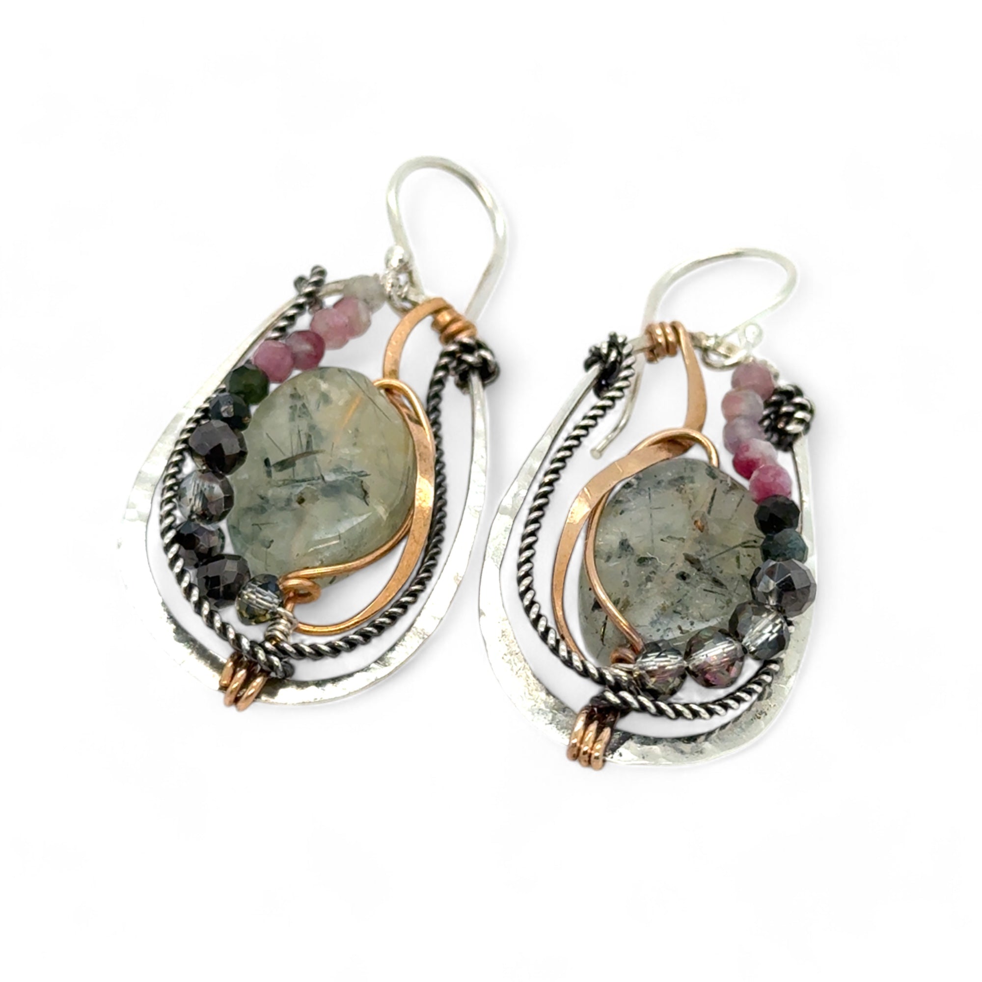 A pair of Prehnite smooth oval earrings with cool inclusions, adorned with hammered bronze, twisted oxidized sterling silver, and micro faceted watermelon tourmaline gemstones, attached to sterling silver French hooks.