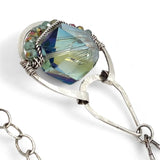 A sterling silver necklace with a box chain and an oval citrus crystal pendant, surrounded by smaller faceted crystals.