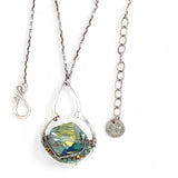 A sterling silver necklace with a box chain and an oval citrus crystal pendant, surrounded by smaller faceted crystals.