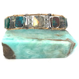 Chrysocolla and flashy labradorite tile gemstones are held within a brass cuff bracelet frame with oxidized sterling silver and gold filled wire accents