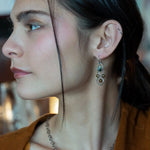 A pair of sterling silver chandelier earrings with brown fresh water pearl dangles and a central cat's eye faceted gemstone.