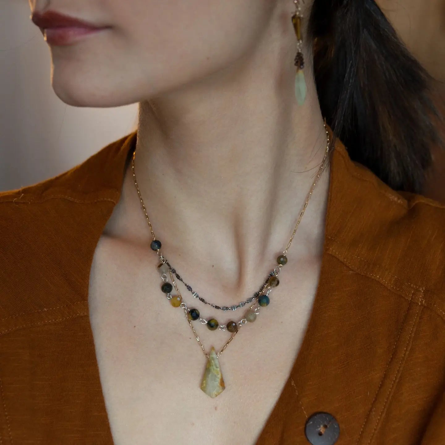 Green yellow jade long diamond hangs from gold filled box chain, with a layer of cat's eye gemstones, and a layer of oxidized sterling silver chain necklace
