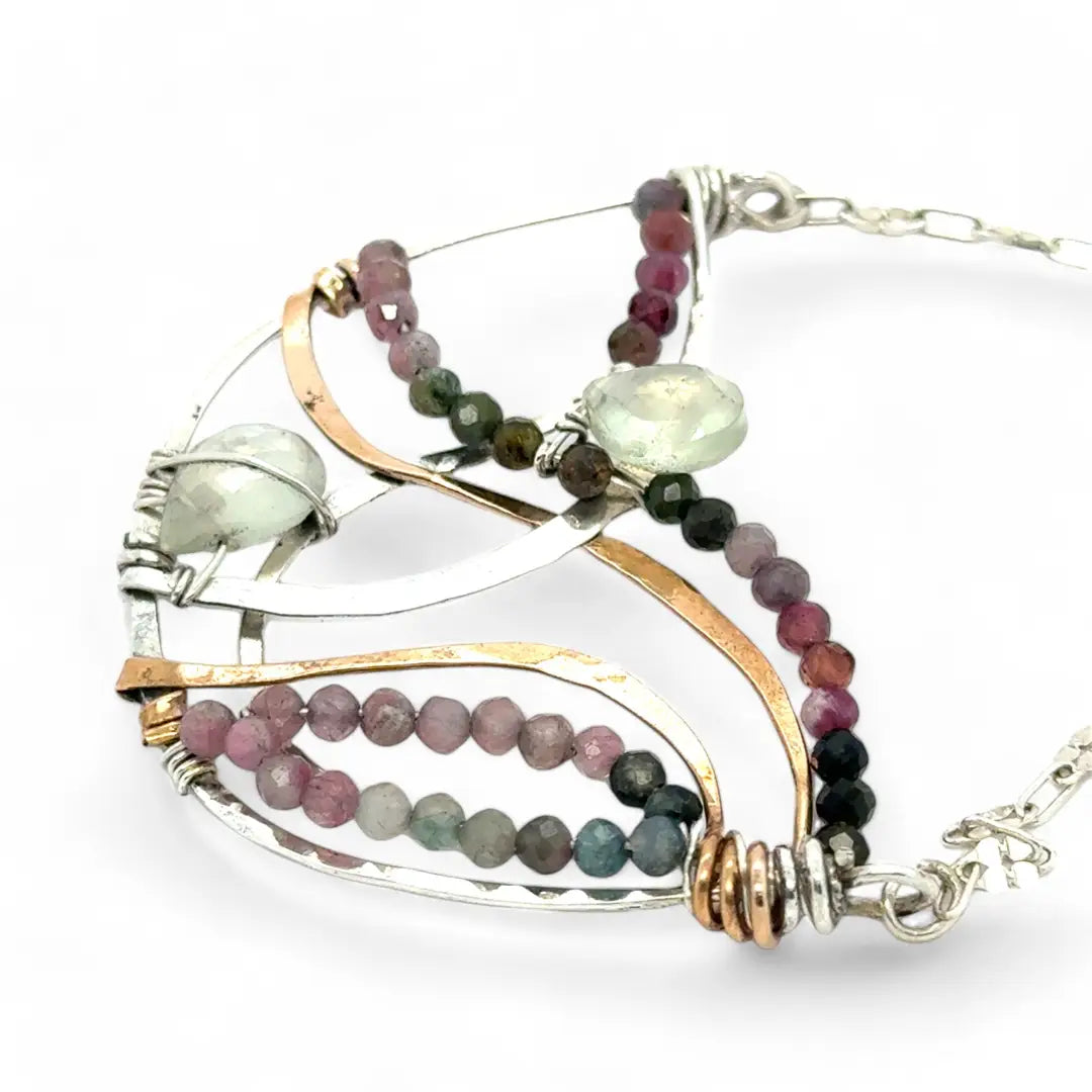 Two prehnite faceted gemstone drops are held within layers of mixed tourmaline, sterling silver, and bronze hammered metal to form our rainbows of tourmaline necklace