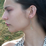 A pair of earrings featuring shiny brass rectangles attached to oxidized sterling silver chains, with gold filled French hooks.