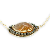A large, smooth citrine nugget sits at the center of a brass hammered pendant necklace, with pyrite accents