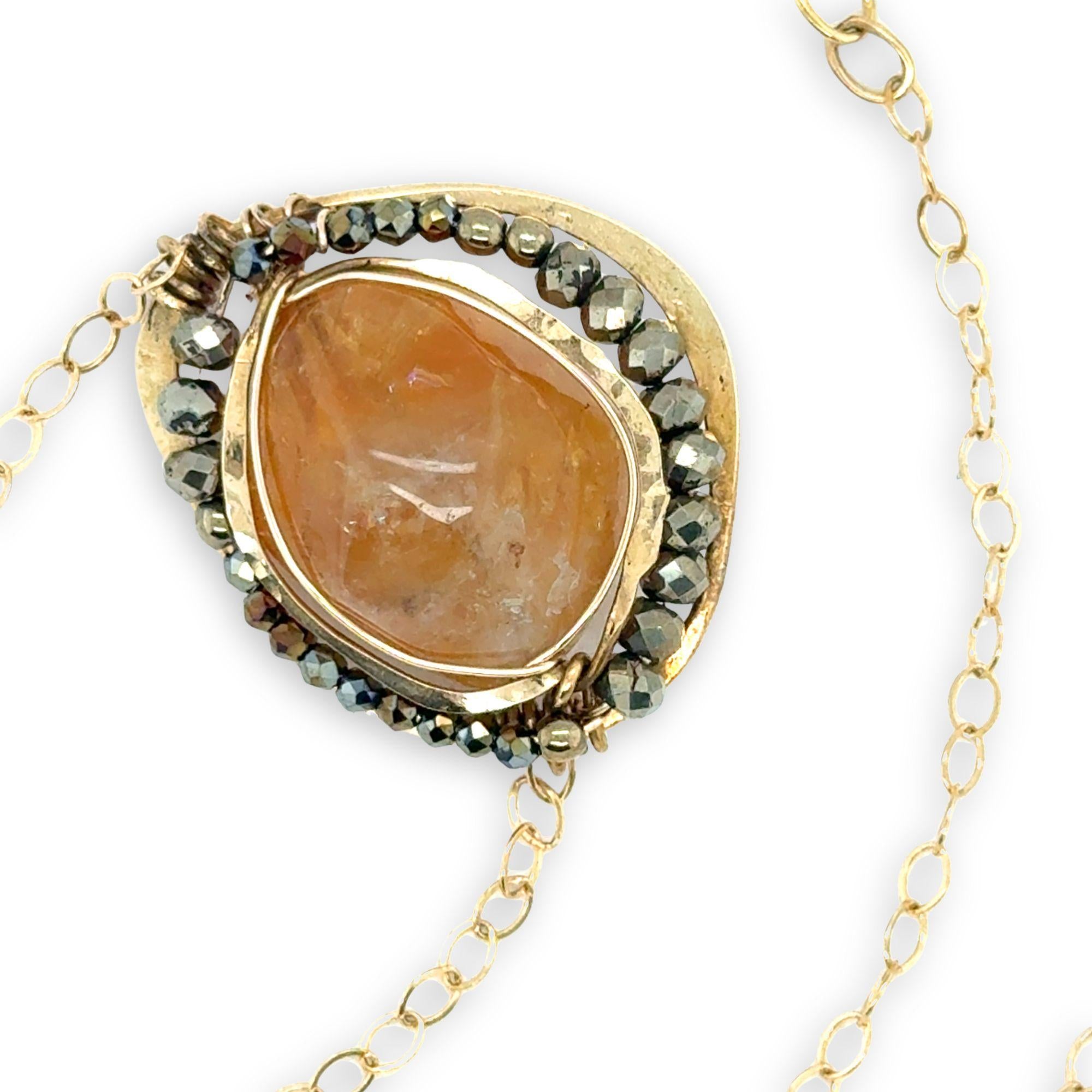 A large, smooth citrine nugget sits at the center of a brass hammered pendant necklace, with pyrite accents