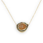 A large, smooth citrine nugget sits at the center of a brass hammered pendant necklace, with pyrite accents