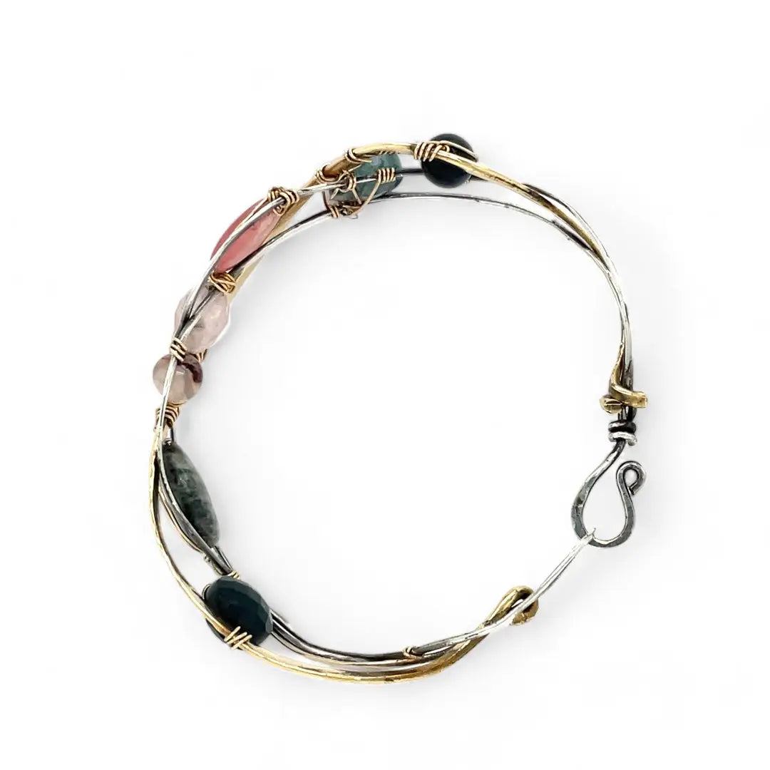 A oxidized sterling. brass, and sterling silver hammered wave bracelet featuring rhodochrosite, rose quartz, bloodstone, moss agate, and jasper gemstones on gold filled wire