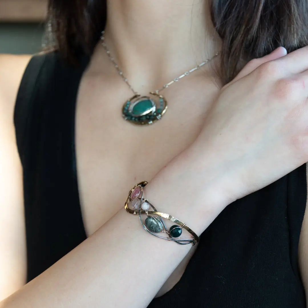A oxidized sterling. brass, and sterling silver hammered wave bracelet featuring rhodochrosite, rose quartz, bloodstone, moss agate, and jasper gemstones on gold filled wire