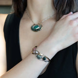 A oxidized sterling. brass, and sterling silver hammered wave bracelet featuring rhodochrosite, rose quartz, bloodstone, moss agate, and jasper gemstones on gold filled wire